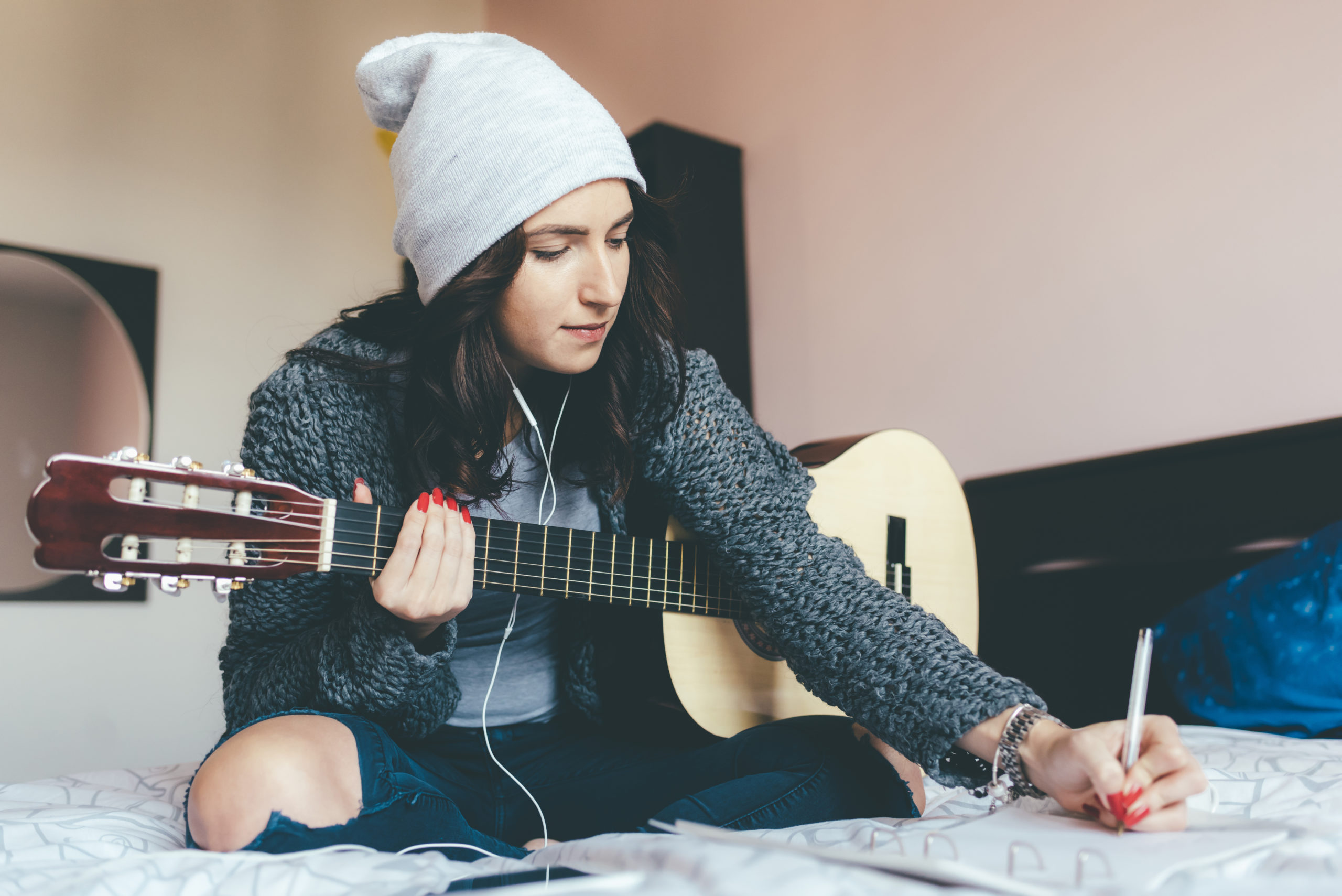 imagen de una mujer joven sosteniendo una guitarra y componiendo música | Colorado guitar lessons adults youth